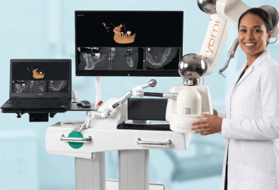 A dental provider standing next to the Yomi robotic-assisted dental surgery system with digital scans on monitors, ensuring gentle treatment for anxious patients.